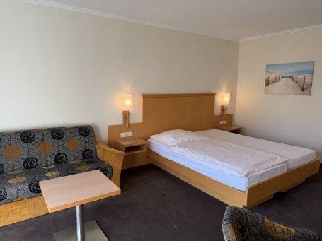 Gemütliches Hotelzimmer mit Doppelbett, Couch und Tisch.