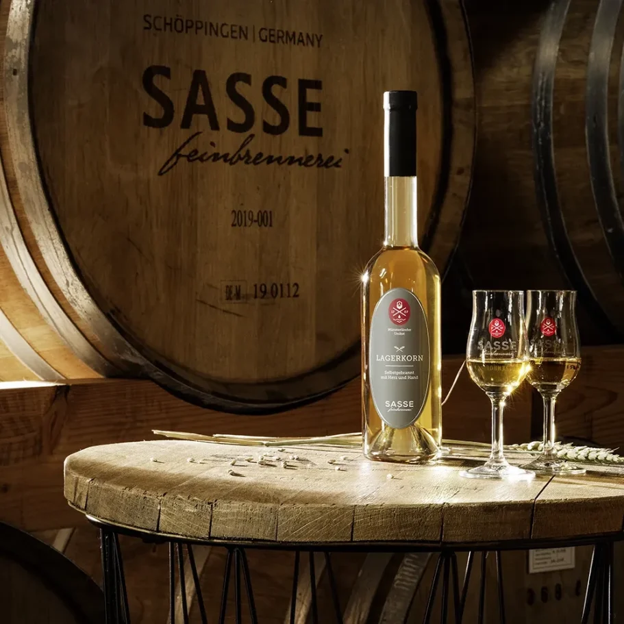 Lagerkorn von Sasse Flasche Lagerkorn und zwei Gläser auf einem Tisch vor Holzfässern im "Reifugium"