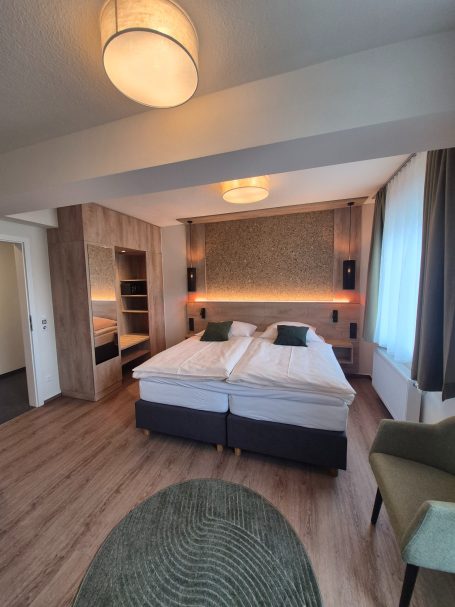 Helles Hotelzimmer mit zwei Einzelbetten, eleganter Einrichtung und moderner Beleuchtung.