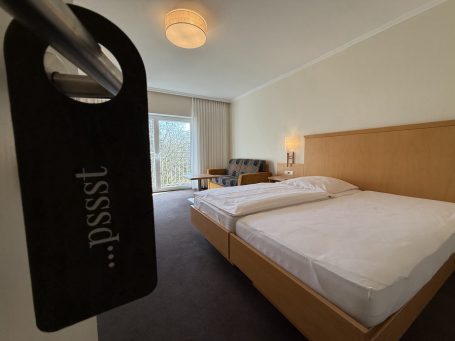 Blick auf ein Hotelzimmer mit zwei Betten und einem "Bitte nicht stören"-Schild.