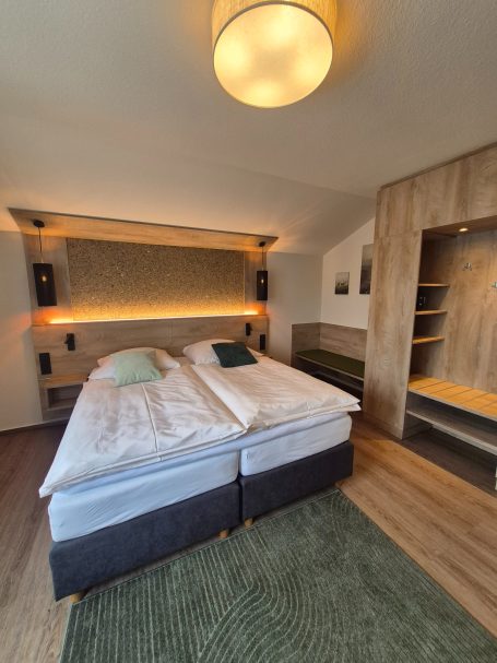 Helles Schlafzimmer mit Doppelbett, Holzregalen und entspannender Atmosphäre.